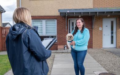 A woman with a dog smiling at a housing officer